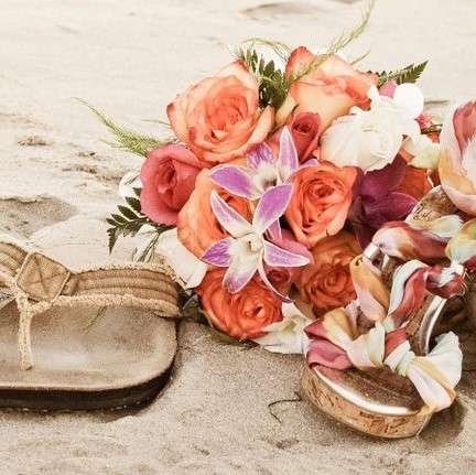 wedding couple's sandals on beach with peach and pink flower bouquet