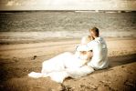 wedding couple sitting on sandy beach at ocean
