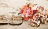wedding couple's sandals on beach with peach and pink flower bouquet
